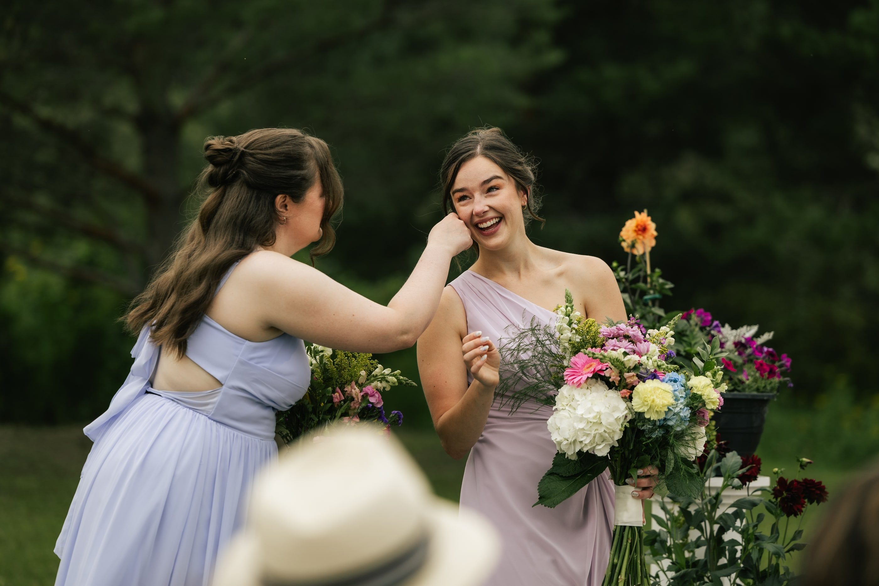 A bridesmaid in lavender wipes away a happy tear during the ceremony as another comforts her.