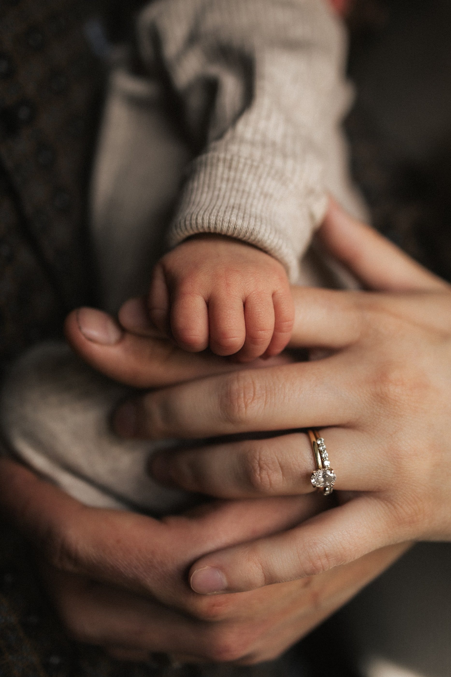 Close-up of a newborn's tiny foot cradled in their parents' hands.