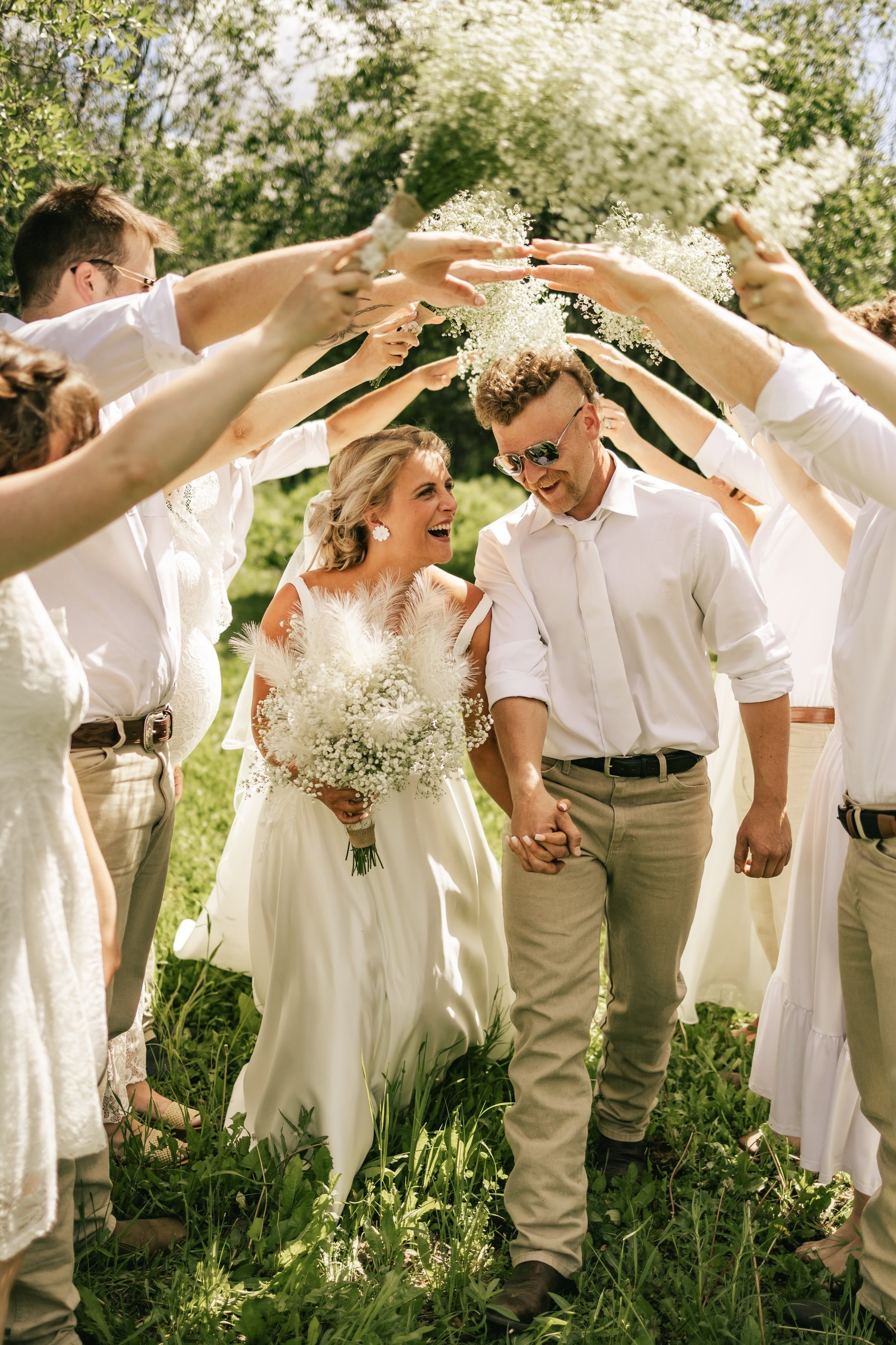 Friends raise their arms into an arch as a smiling bride and groom walk beneath.