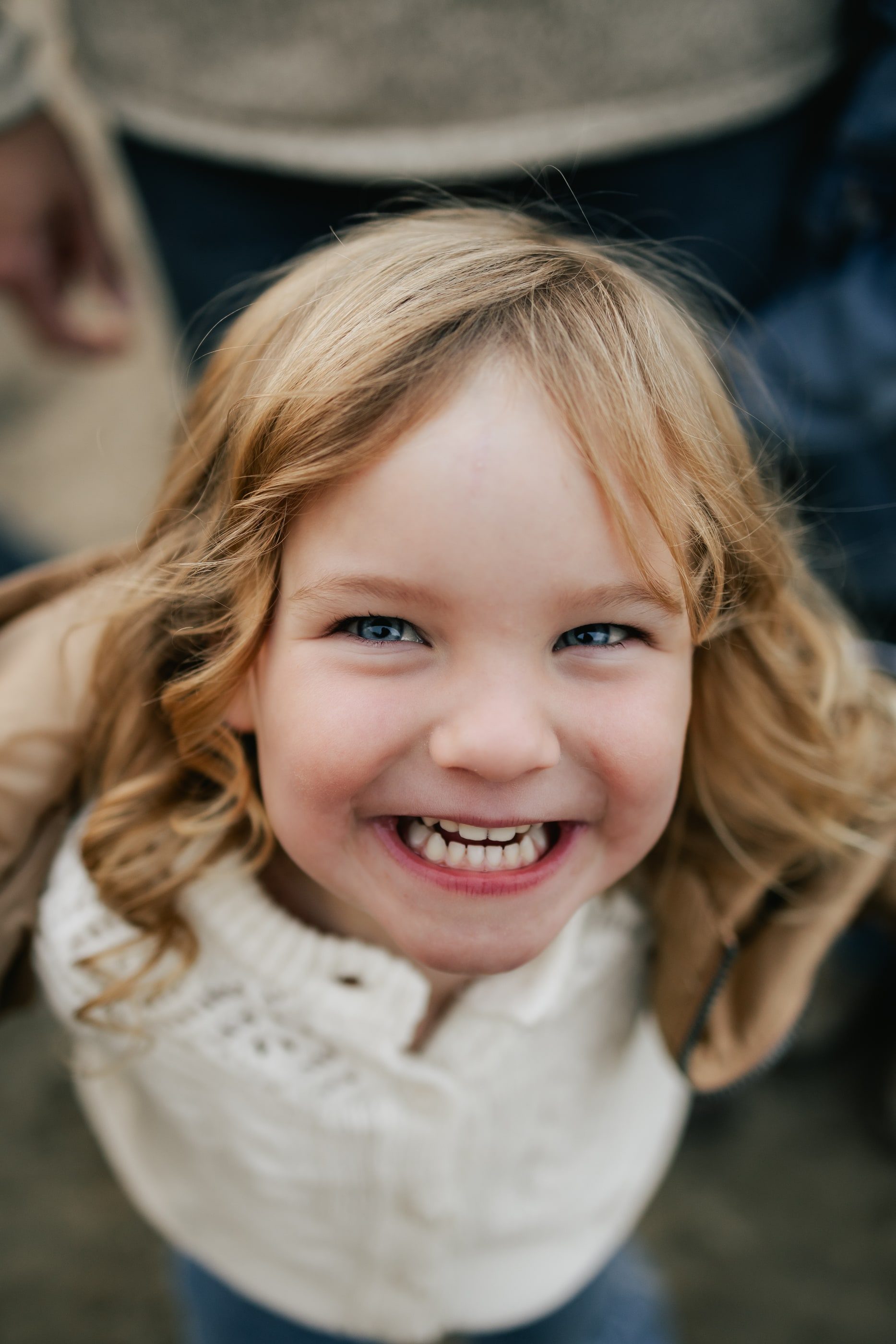 A little girl with curly hair grins up at the camera.